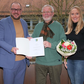 Ulricht Leicht steht mit einer Urkunde in der Hand zwischen Sebastian Straubel und Vanessa Fischer.