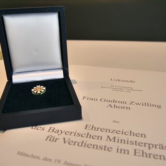 Das Ehrenamts-Ehrenzeichen in seiner blauen Schatulle, sie liegt auf einer Urkunde, dort ist der Name von Gudrun Zwilling zu lesen.