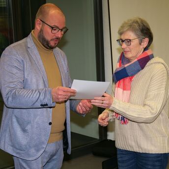 Landrat Sebastian Straubel überreicht einer Frau eine Urkunde.