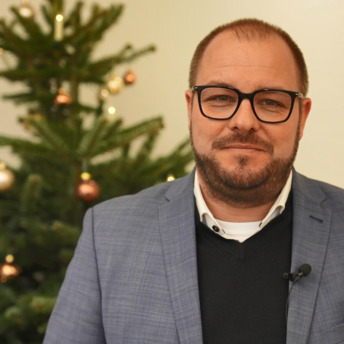 Landrat Sebastian Straubel steht vor einem Weihnachtsbaum.